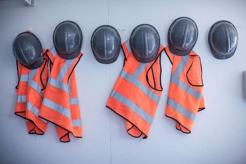 High visibility vests and hard hats hanging on a wall